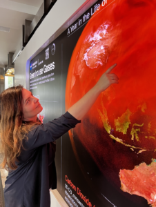 Helen-Nicole Kostis in front of the Greenhouse Gases Dashboard, Hyperwall Display, NASA Earth Information Center. Photo by Brenda Lopez Silva